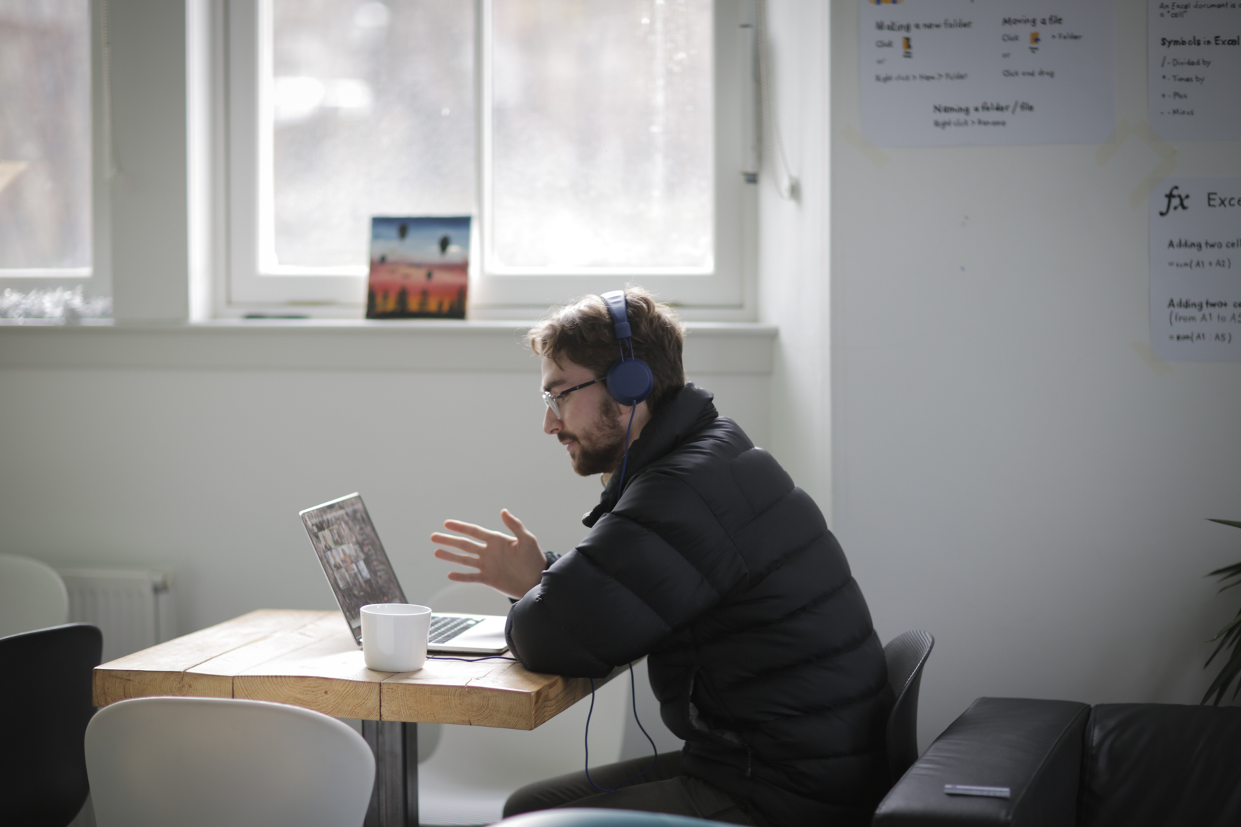 Man on computer call with headphones sitting at table at Go Youth Trust