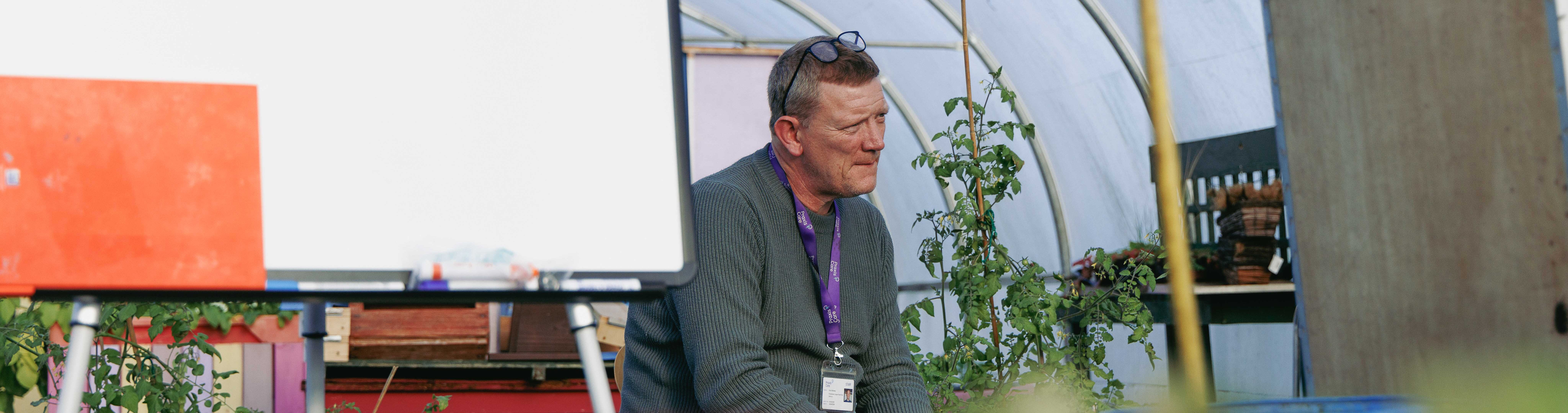 Man sitting by whiteboard in greenhouse at Praxis Northern Ireland