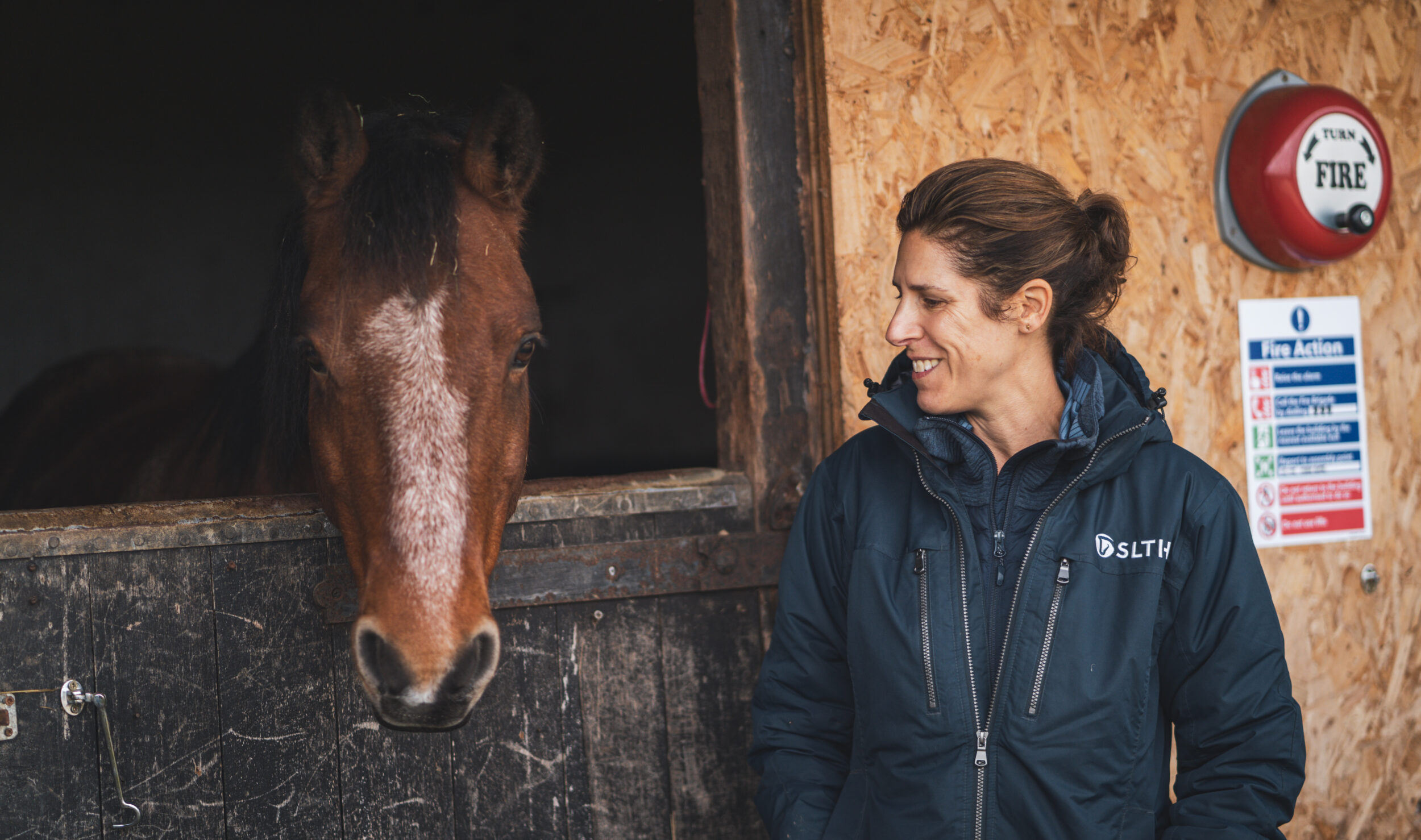 Woman smiling at horse outside horse stables at Strength and Learning Through Horses