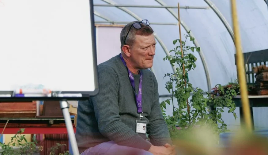 Praxis man sitting in greenhouse with whiteboard